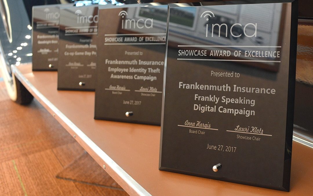 Several Frankenmuth Insurance Excellence Award plaques lined up on the step of an old Model T car.